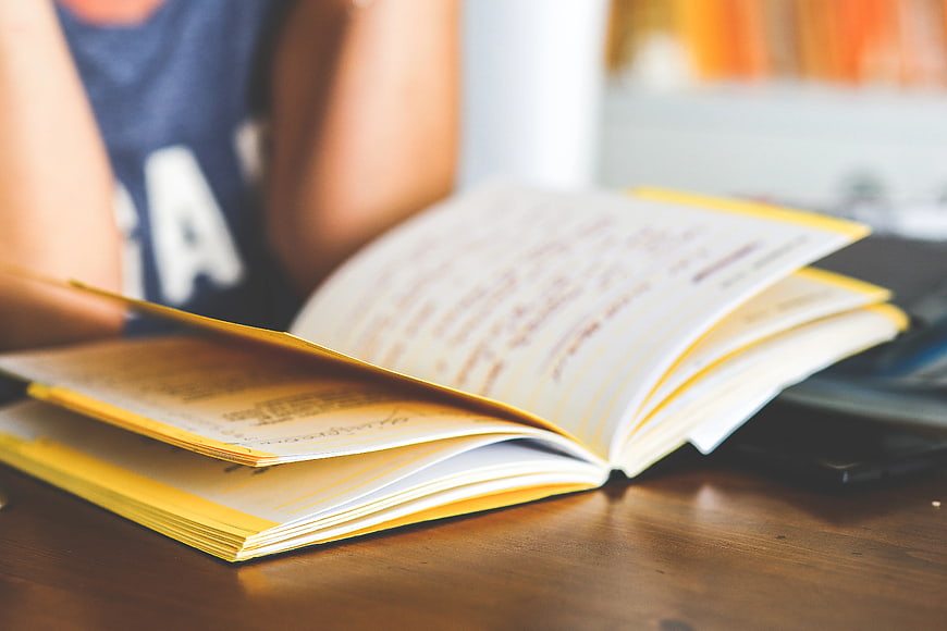Close-up of open notebook with handwritten notes on wooden desk