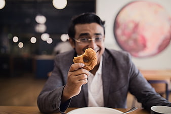 Happy Man Eating Donut in Modern Restaurant