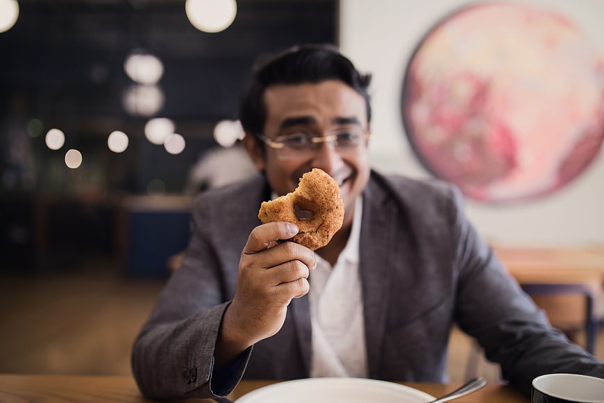 Happy Man Eating Donut in Modern Restaurant
