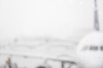 Raindrops on Airport Window with Blurred Airplane Background