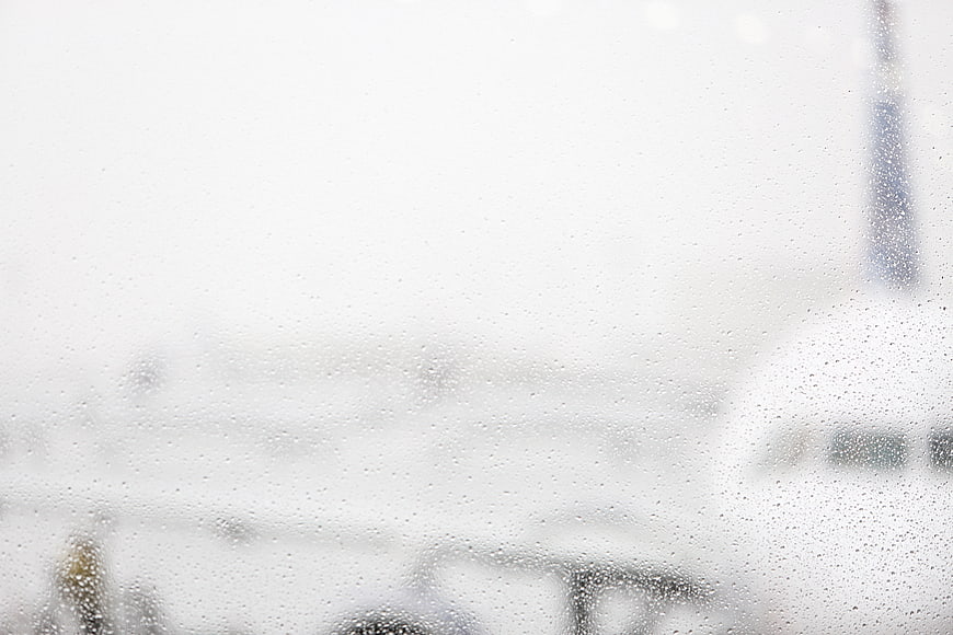 Raindrops on Airport Window with Blurred Airplane Background