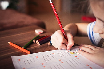 Child practicing handwriting with colored pencils
