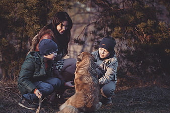 Mother and Two Boys Playing with Dog in Forest