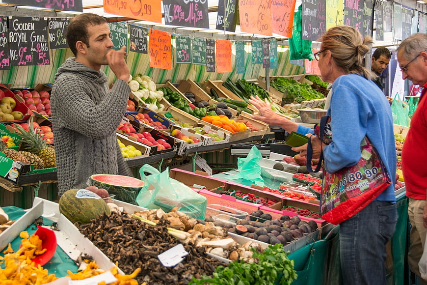 Fresh produce market stall with customers and vendor
