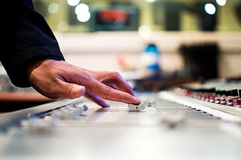Sound Engineer Adjusting Fader on Mixing Console