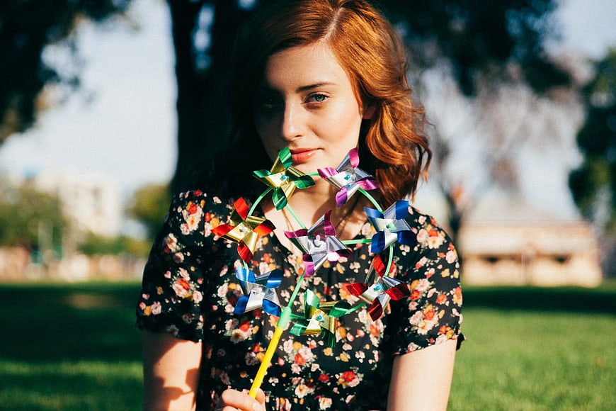 Woman with Red Hair Holding Colorful Pinwheel Toy in Park