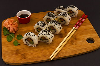 Sushi Rolls With Sesame Seeds On Wooden Board With Chopsticks
