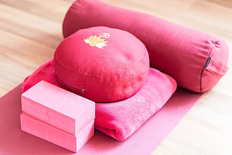 Pink Meditation Cushion, Yoga Bolster, and Blocks on Wooden Floor
