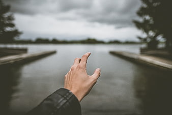 Hand pointing towards lake with wooden docks