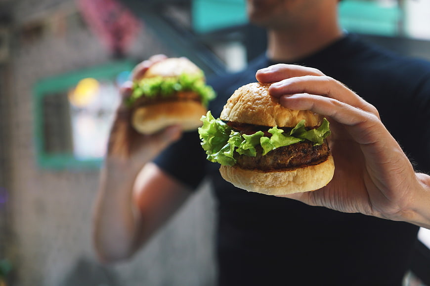 Man Holding Two Burgers with Fresh Lettuce