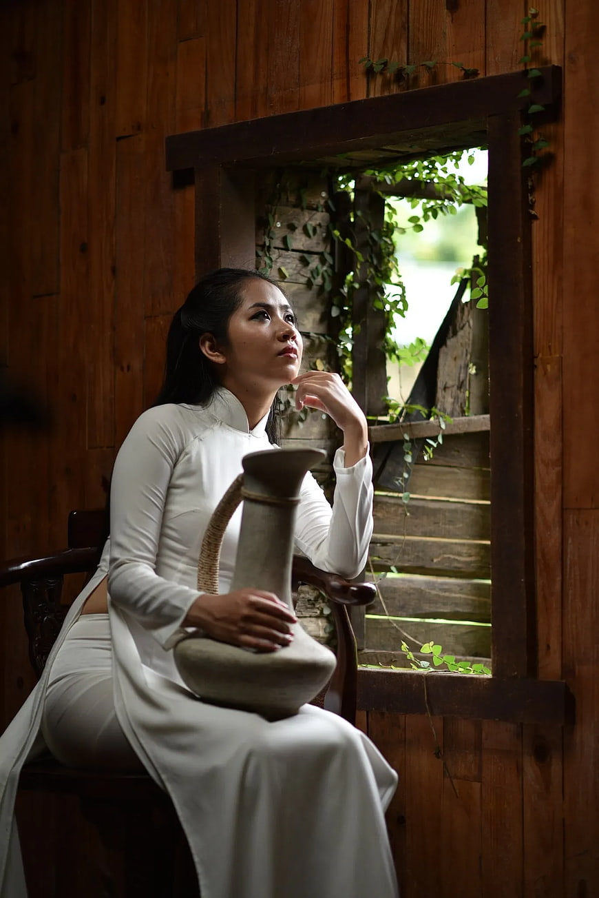 Woman in White Ao Dai Sitting by Wooden Window