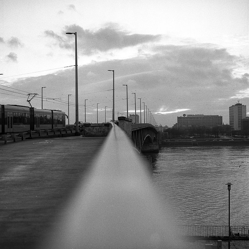 Black and white cityscape with tram and bridge over river