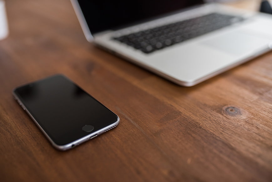 Smartphone and Laptop on Wooden Desk Surface