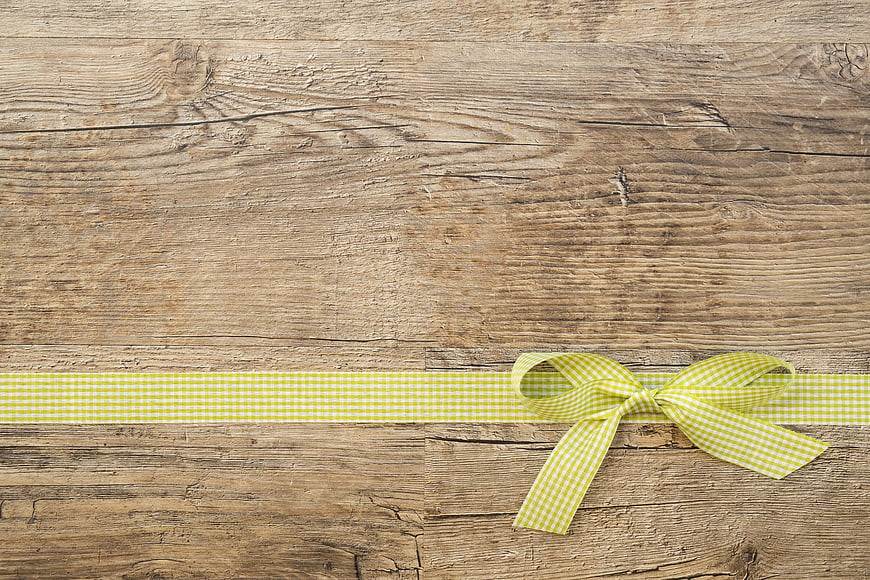 Yellow gingham ribbon bow on rustic wooden background