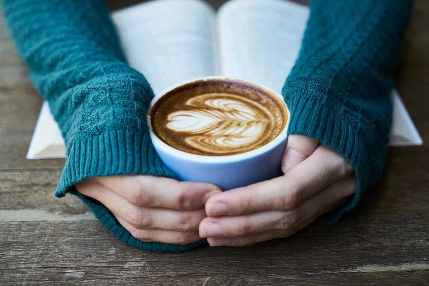 Cozy Hands Holding Coffee Cup with Open Book