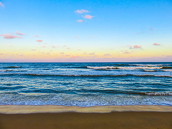 Serene Beach Sunset with Gentle Ocean Waves and Blue Sky