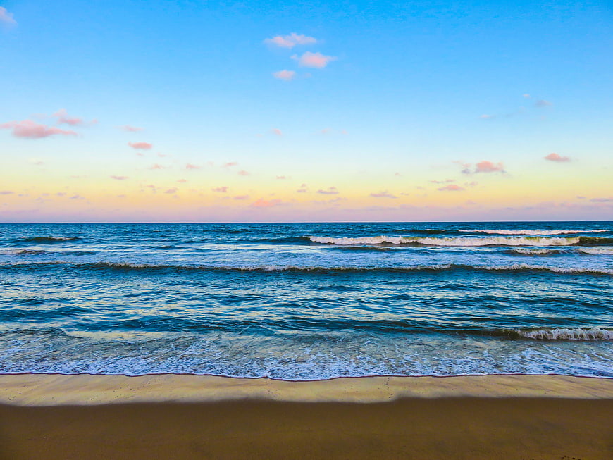 Serene Beach Sunset with Gentle Ocean Waves and Blue Sky