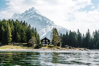 Alpine Lake with Mountain Cabin and Snowy Peak