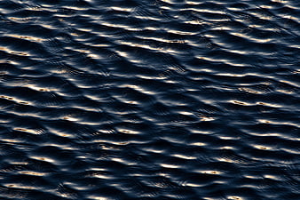 Dark Blue Water Ripples with Golden Sunlight Reflections