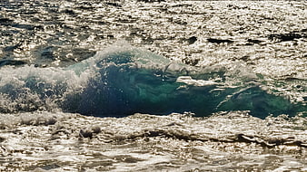 Ocean wave crashing with sparkling sunlight on water surface