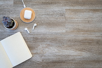 Minimalist workspace flat lay with notebook, succulent, and wireless earbuds