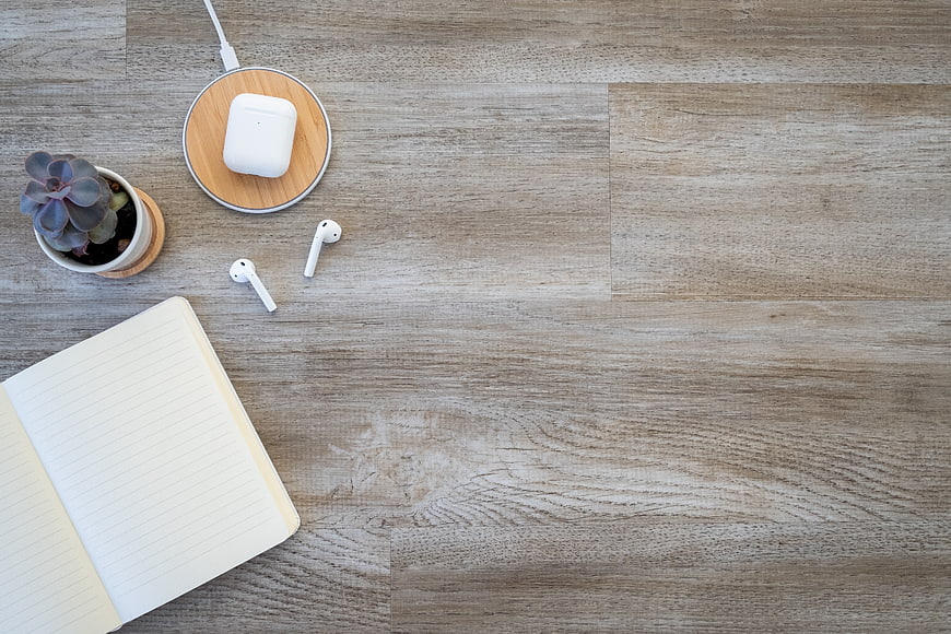 Minimalist workspace flat lay with notebook, succulent, and wireless earbuds