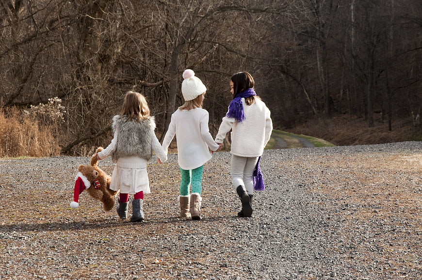 Three young girls walking together on a gravel path in winter