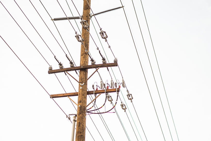 Wooden Utility Pole with Power Lines Against White Sky