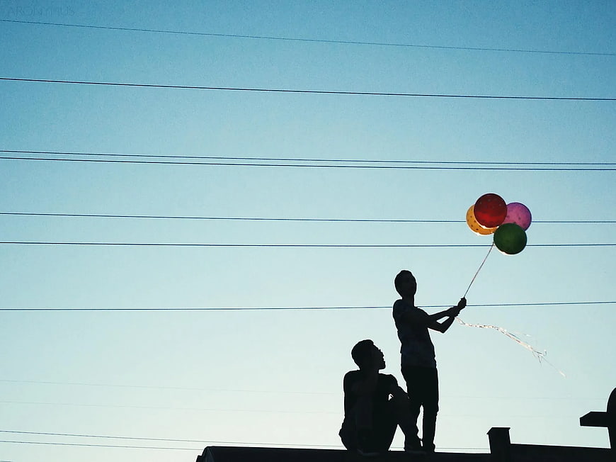 Silhouette of Two Boys with Balloons on a Rooftop