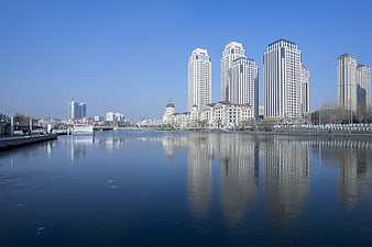 Modern city skyline reflected in calm river water