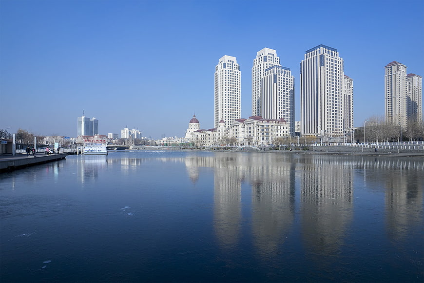 Modern city skyline reflected in calm river water