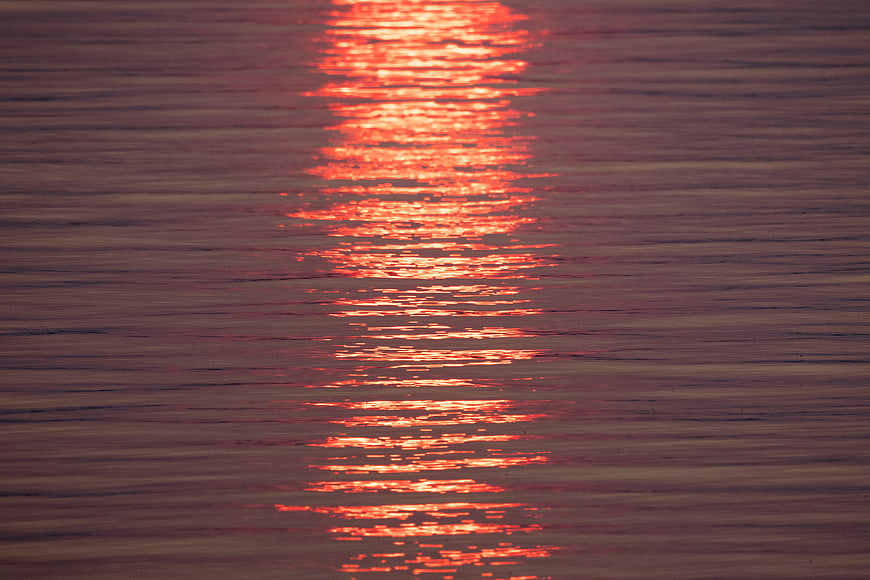 Vibrant orange sunset reflection on rippling water surface