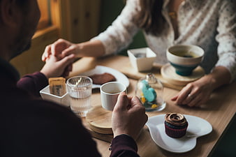 Couple holding hands over coffee and cupcakes in cafe
