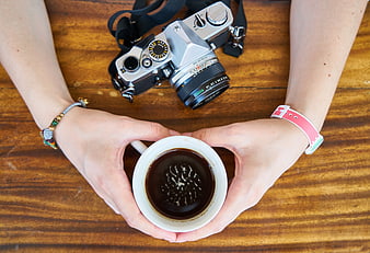 Top View of Hands Holding Coffee Cup with Vintage Camera