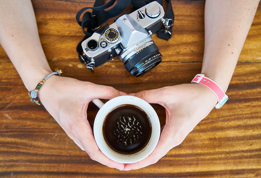 Top View of Hands Holding Coffee Cup with Vintage Camera