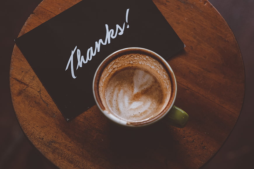 Top View of Coffee Cup and Black Thanks Card on Wooden Table