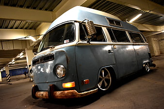 Vintage Blue VW Bus with Rust and Custom Wheels in Parking Garage
