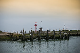 Wooden pier extending into calm water with red lighthouse