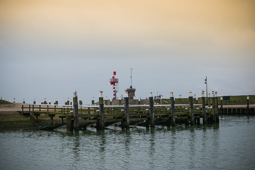 Wooden pier extending into calm water with red lighthouse