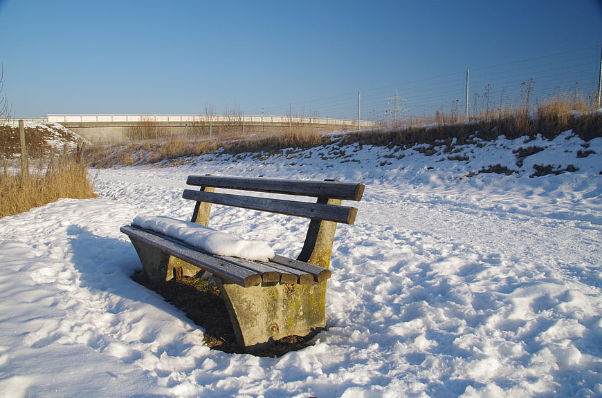 Lonely wooden bench covered in snow during winter
