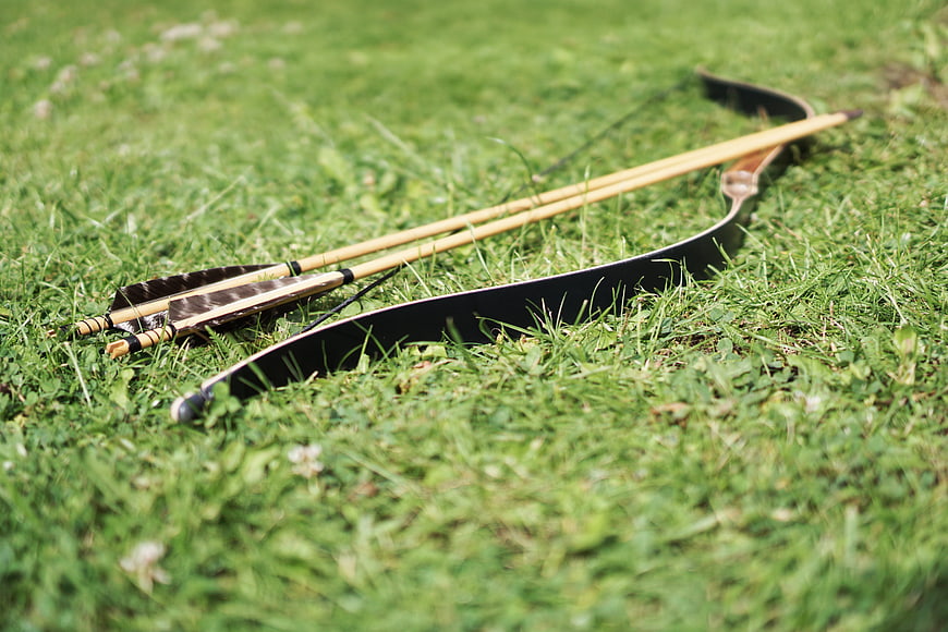 Traditional recurve bow and arrows resting on green grass