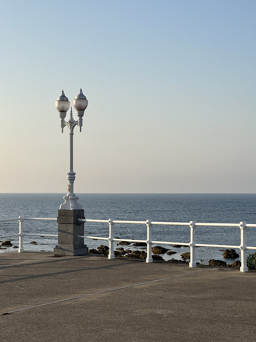 Vintage white lamp post on seaside promenade with ocean view