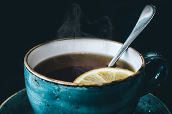 Steaming cup of hot tea with lemon slice in blue ceramic mug
