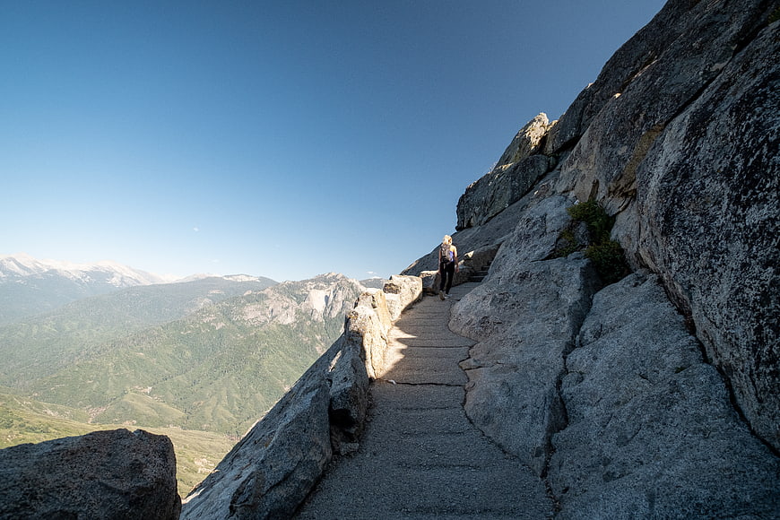 Woman hiking on mountain trail with scenic valley view