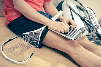 Tennis Player Typing on Laptop with Racket