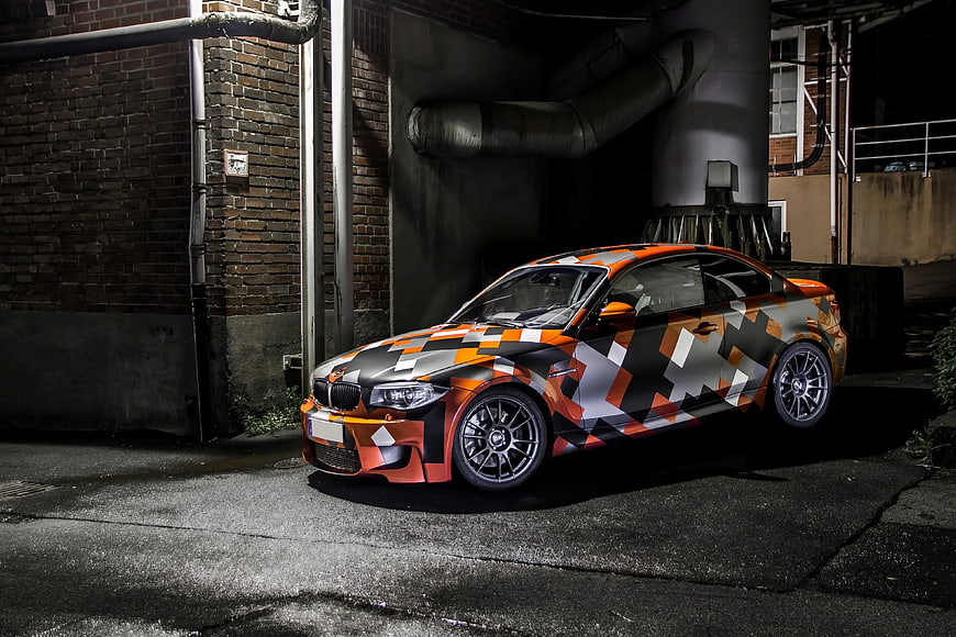 Orange and Black Camouflage Sports Car in Industrial Setting