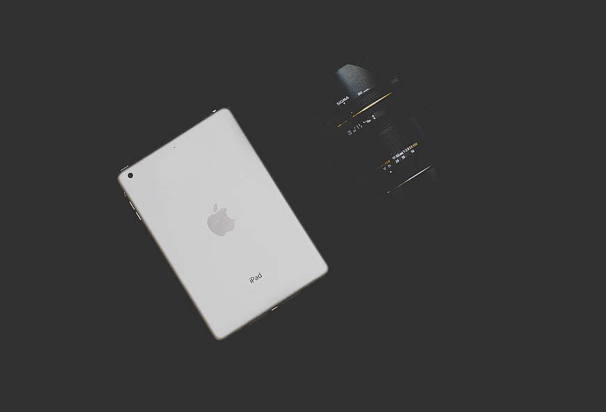 White iPad and Sigma Camera Lens on Dark Background