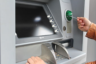 Hand inserting bank card into ATM machine slot
