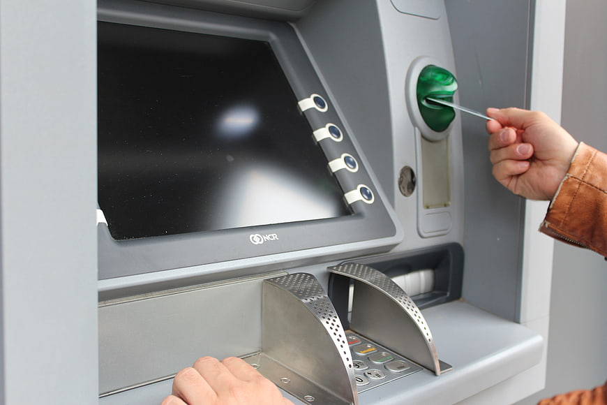 Hand inserting bank card into ATM machine slot
