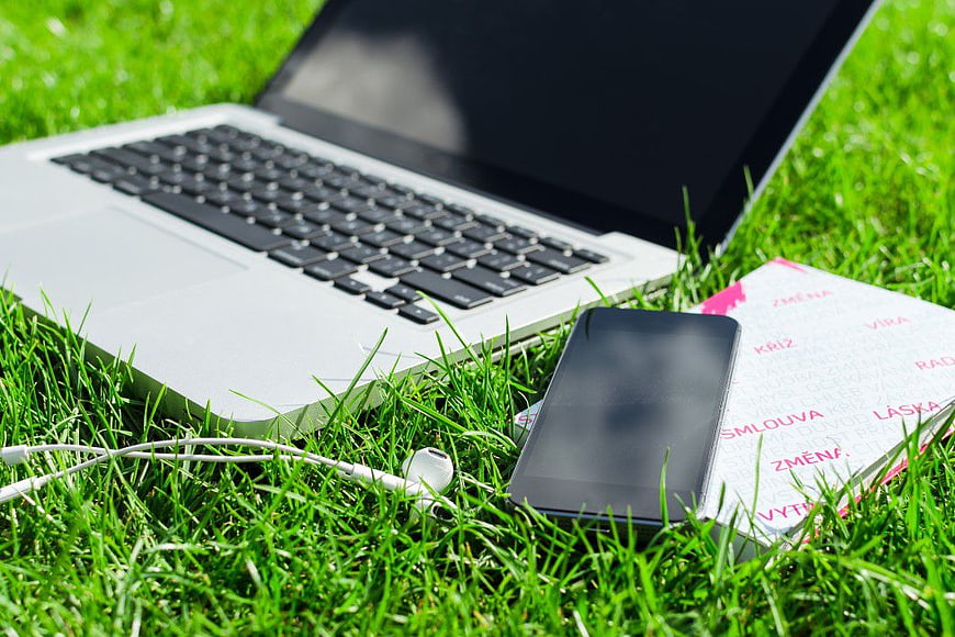 Laptop, Smartphone, and Book on Green Grass